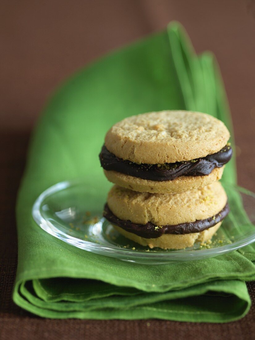 Two Chocolate Ganache Sandwich Cookies Stacked on a Glass Plate