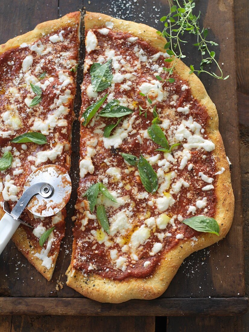 Pizza mit Mozzarella, Basilikum und Tomatensauce auf Schneidebrett