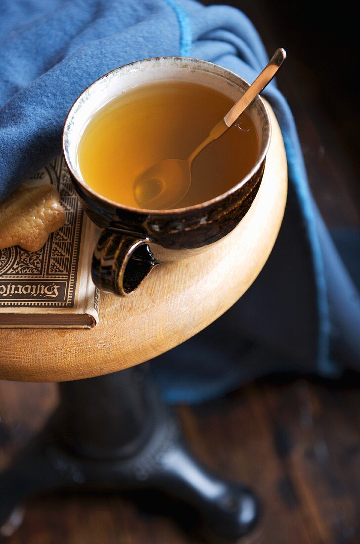 Brown ceramic cup of hot tea and biscuit on chair