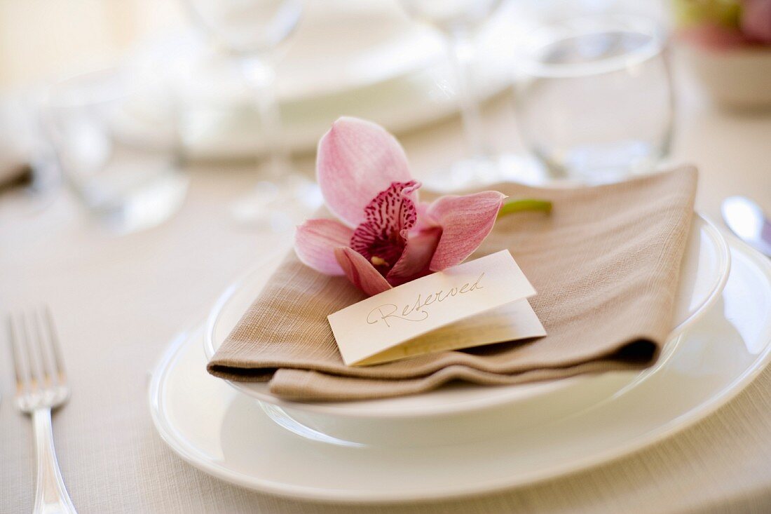 A place setting with place card and an orchid flower