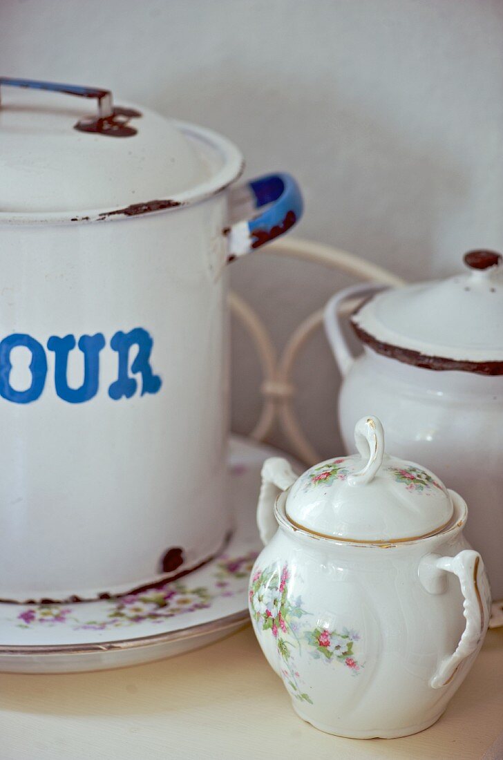 Vintage floral sugar bowl in front of enamel pots