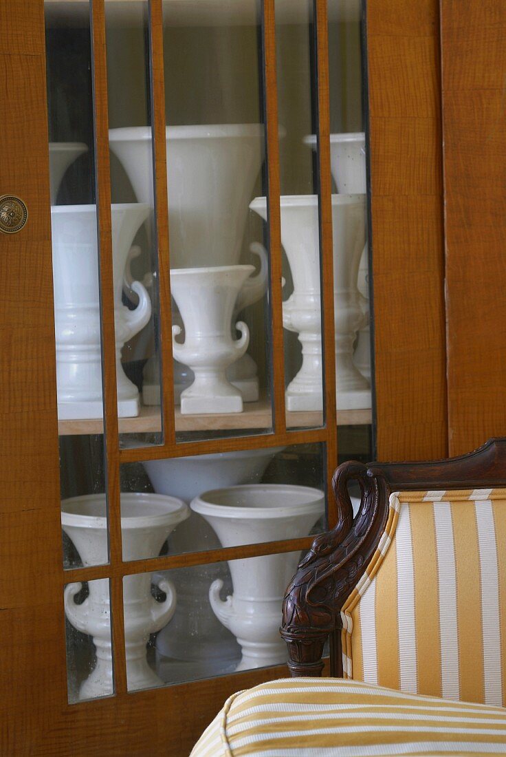 Blick durch Glastür eines Biedermeier Schrank auf weiße Porzellan Vasensammlung