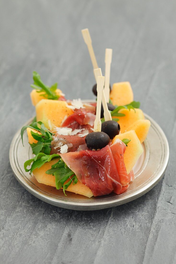 Melon slices with prosciutto and olives