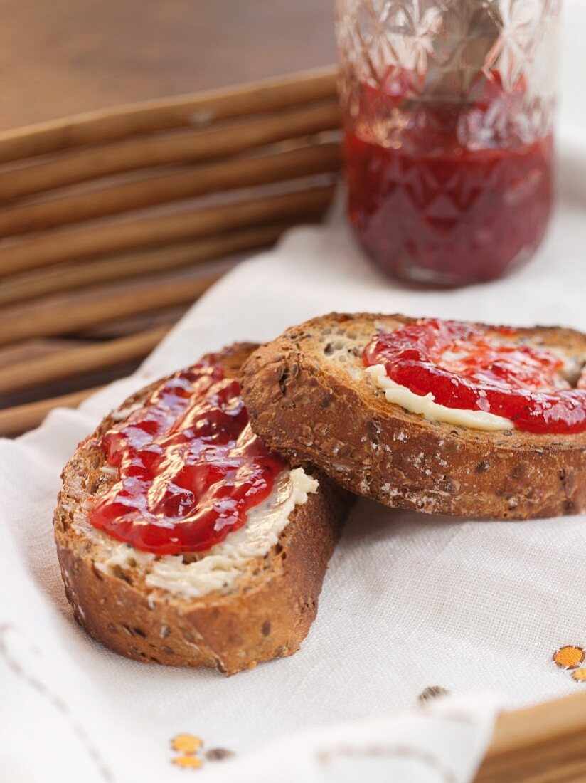 Two Slices of Multi-Grain Toast with Butter and Strawberry Jam