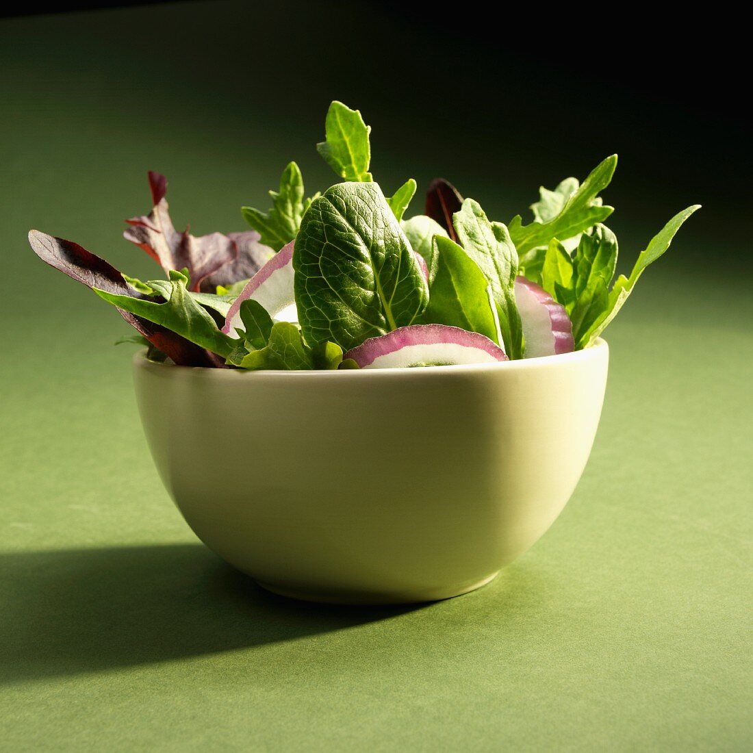 Mixed Greens Salad with Red Onions on a Green Background