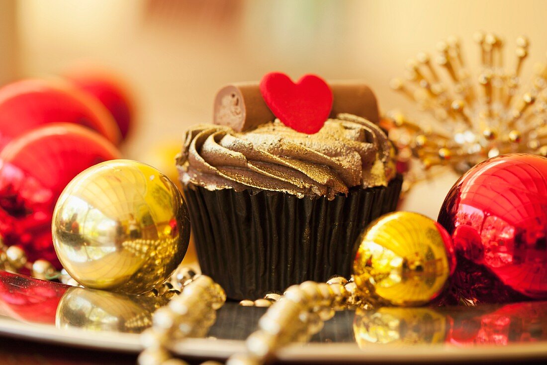 A gold cupcake with a heart and baubles