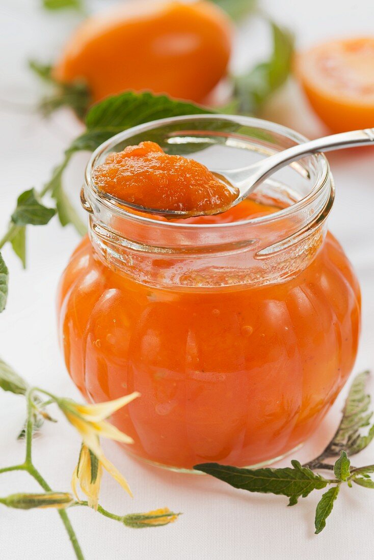 Yellow tomato jam in a jar and on a spoon