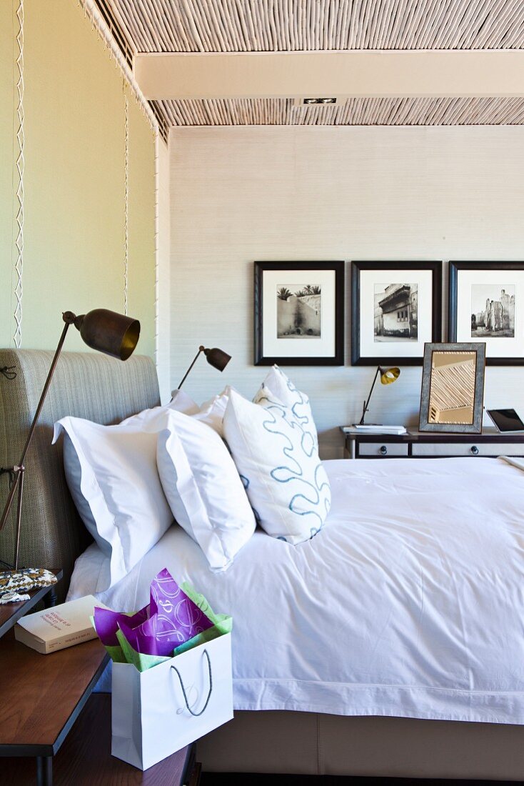 Doppelbett mit gepolstertem Kopfteil und Kissen zwischen Retro Metall Tischlampen auf Nachttisch in modernem Schlafzimmer