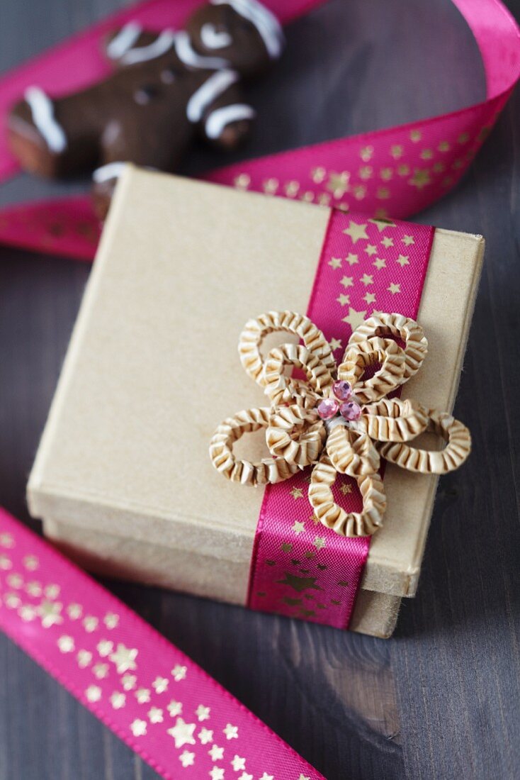 Geschenkschachtel mit pinkfarbenem Sternenband und Pappschleife