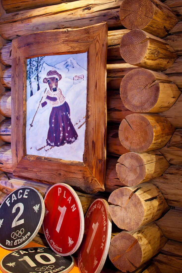 Gemaltes Bild in rustikalem Holzrahmen mit Tiermotiv in Nostalgischer Kleidung beim Skifahren an Blockhauswand