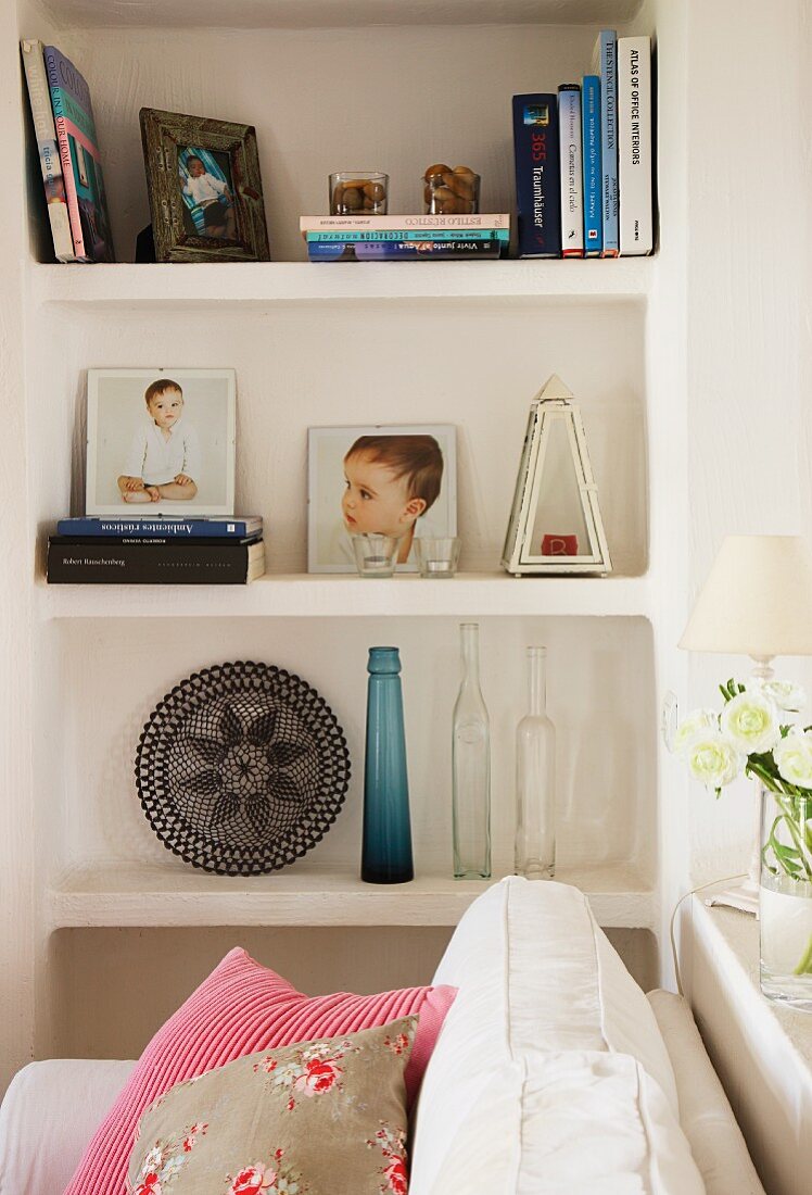 Sofa next to a built-in, brick shelves with photographs in front of a wall niche