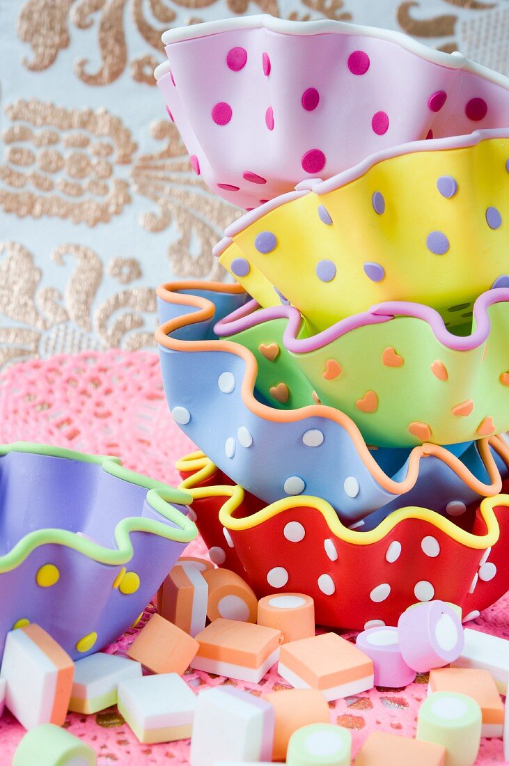 A stack of colourful spotted cupcake moulds and some sweets