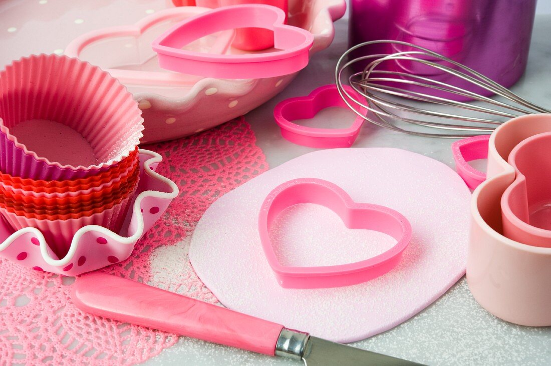 Pink cutters, baking moulds, egg whisk and knife