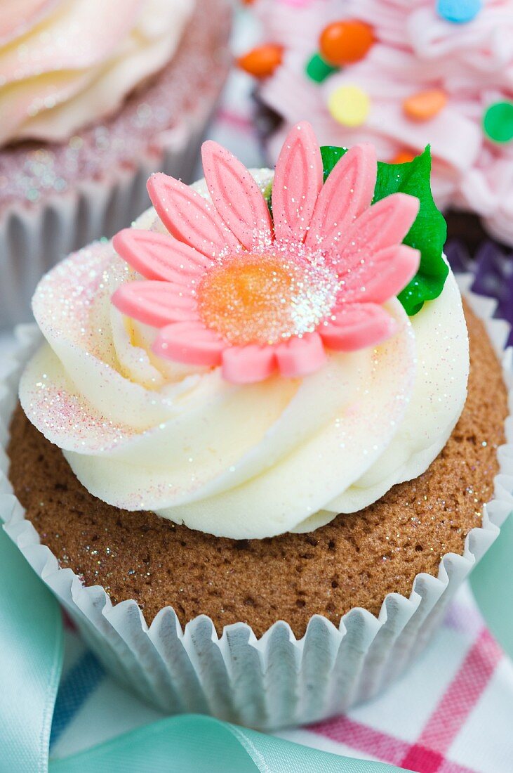 A vanilla cupcake with a pink sugar flower