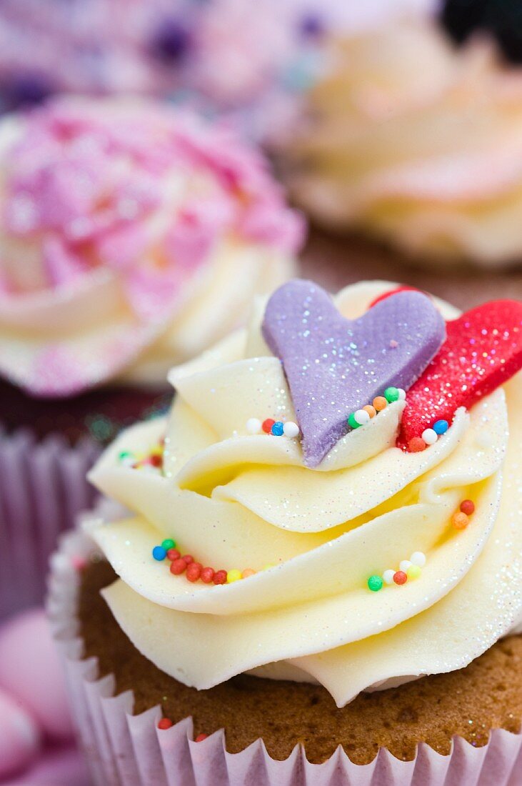 Vanille-Cupcake mit Herzen und bunten Zuckerperlen
