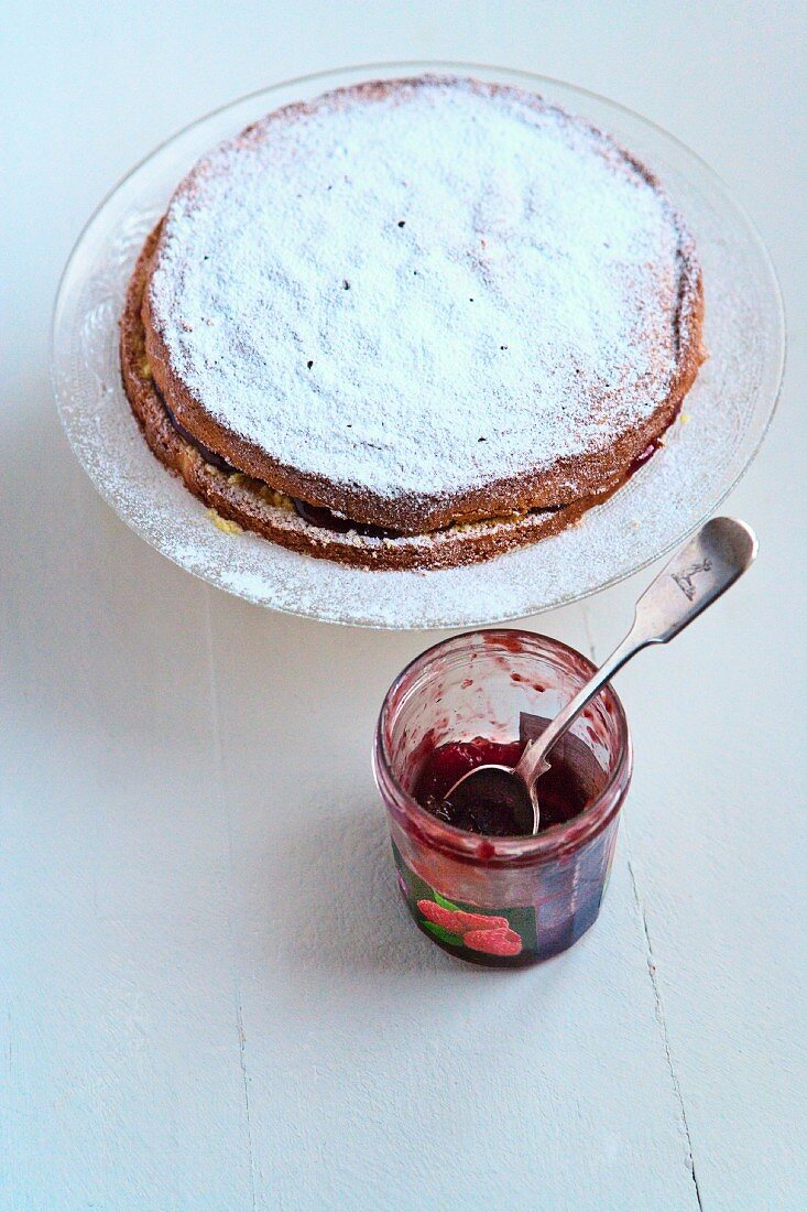 Sponge cake filled with raspberry jam and a jam jar