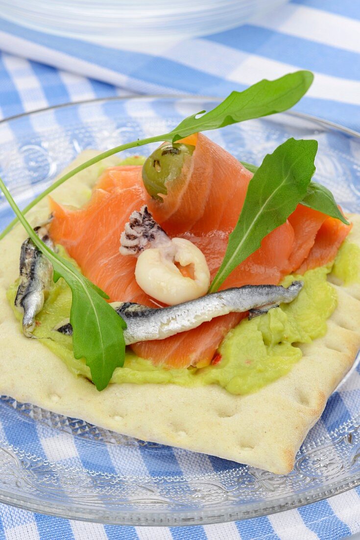 Crisp bread topped with guacamole, salmon, anchovies and seafood