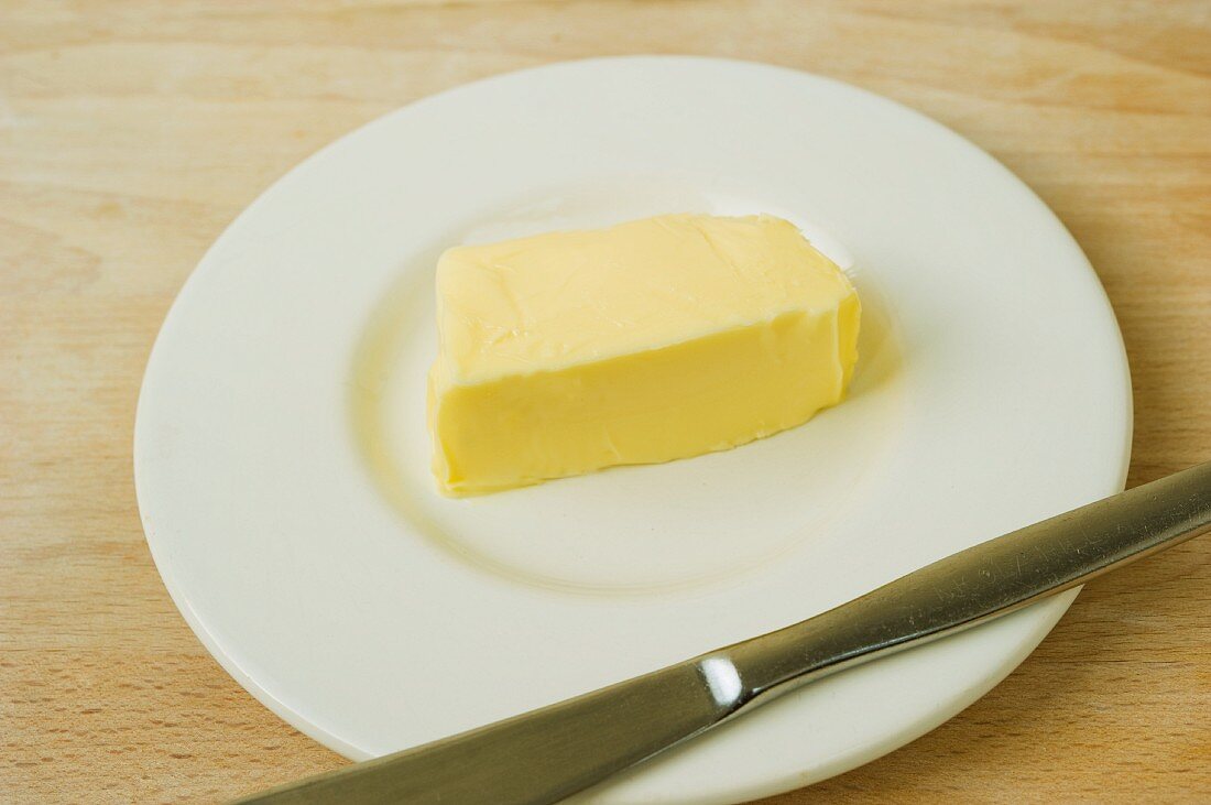 A pat of butter on a plate with a knife