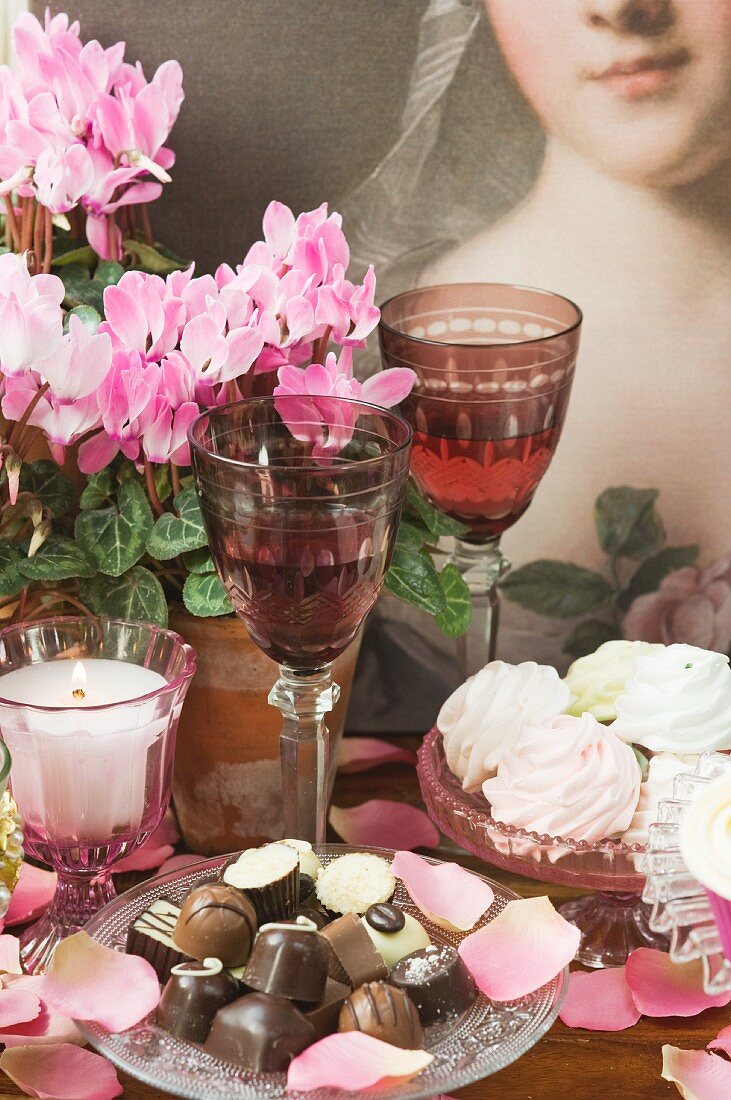 Meringues, chocolates, wine glasses, candles and potted cyclamen