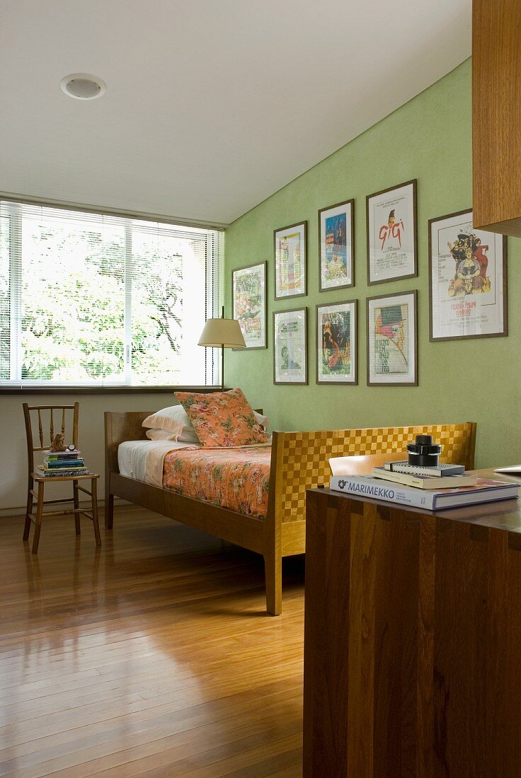 Bedroom with skilfully crafted bed in front of framed posters on wall painted lime green
