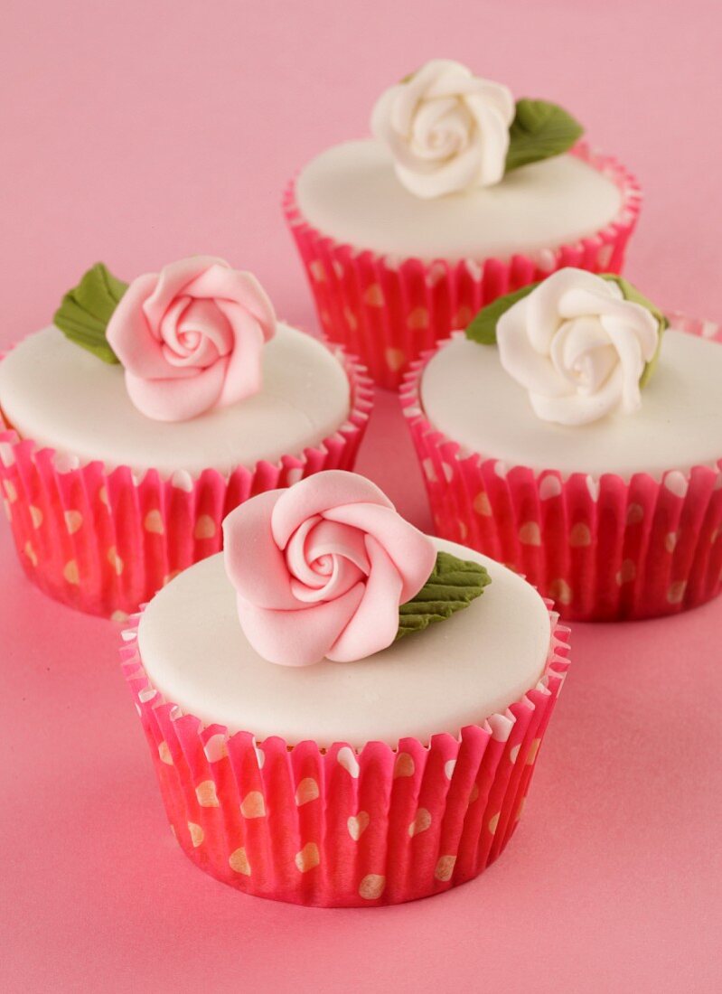 Cupcakes topped with white glaze and sugar roses