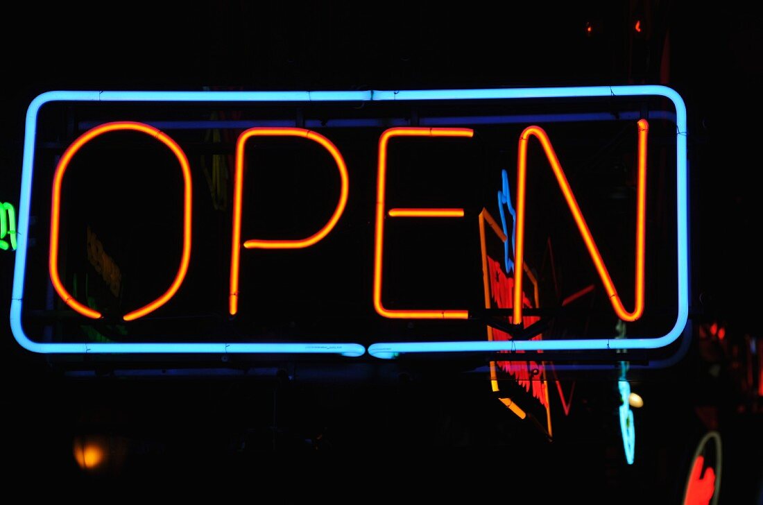 A neon sign outside a pub in the evening