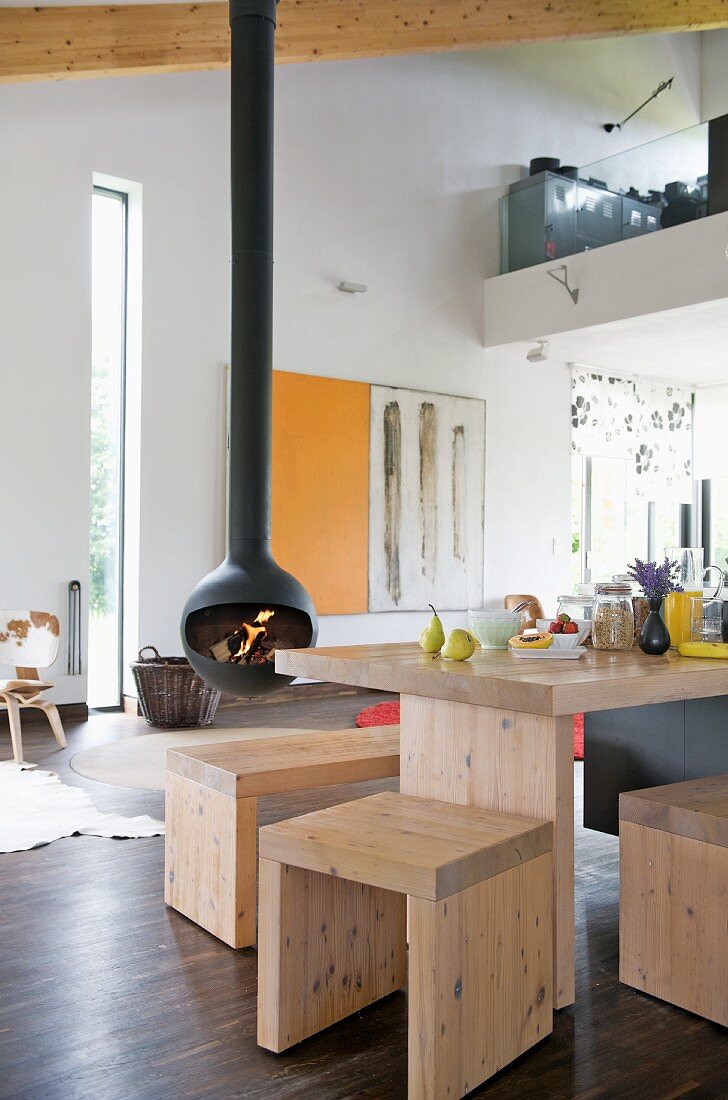 Schlichte Hocker und Tisch aus hellem Holz in offenem Wohnraum mit Kamin (Chimney Anthrax Bubble von Andrea Crosetta)