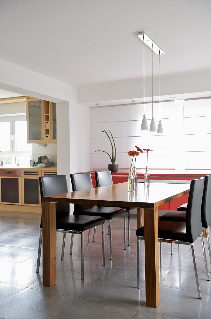 Designer dining area in open-plan interior with view of kitchen counter through wide doorway