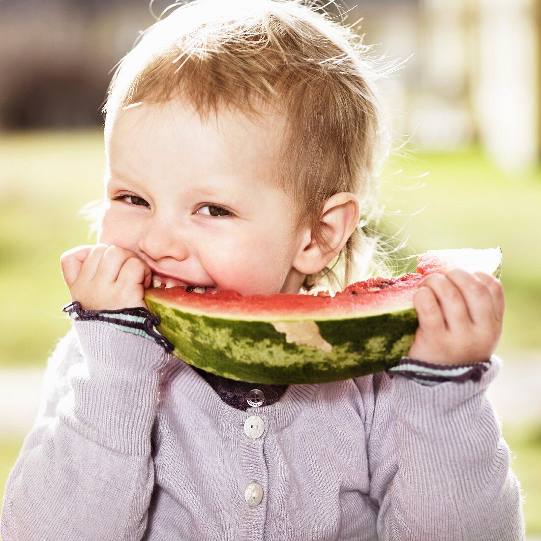 A little girl eating a slice of watermelon