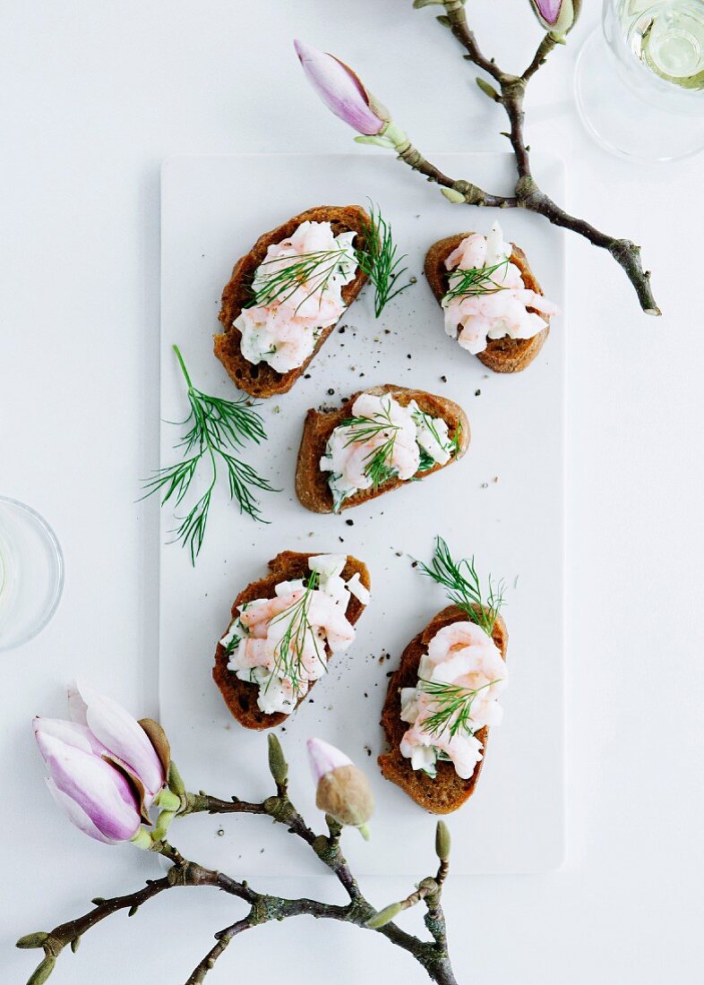 Slices of bread topped with prawns and dill
