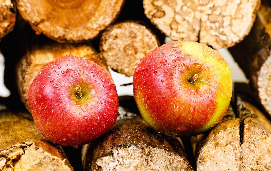 Red apples with droplets of water on a stack of wood