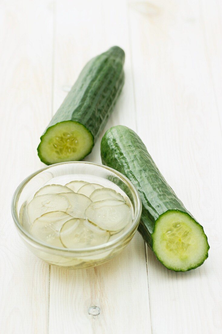 Two cucumbers and a dish of pickled cucumber slices
