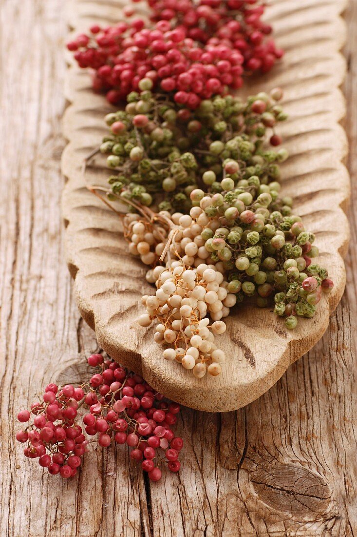 Peppercorns on the vine (red, white and green) in a wooden dish