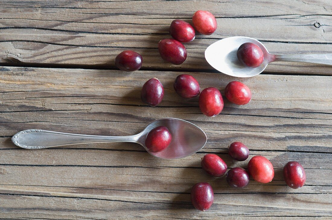 Cranberries and two spoons on a wooden surface