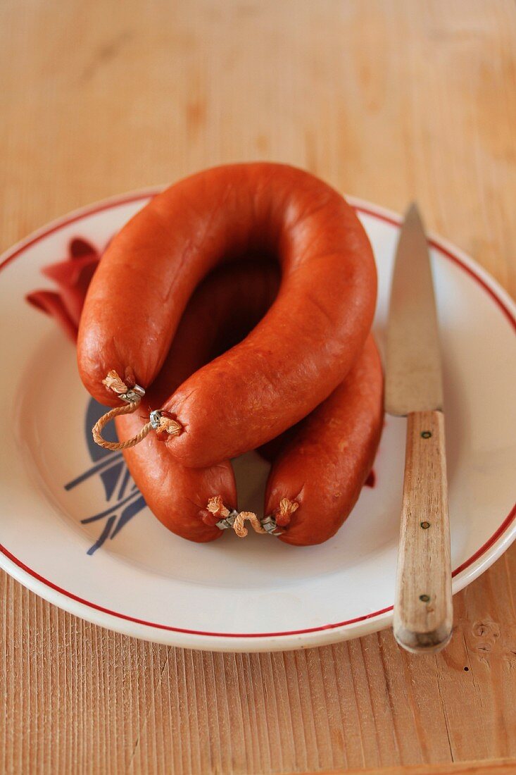 Two home-made sausages on a plate with a knife