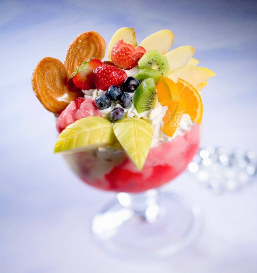 A giant ice cream sundae with strawberry ice cream, cream and lavish fruit decoration