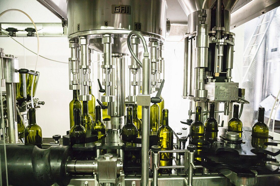 Bottles being filled with wine by a machine