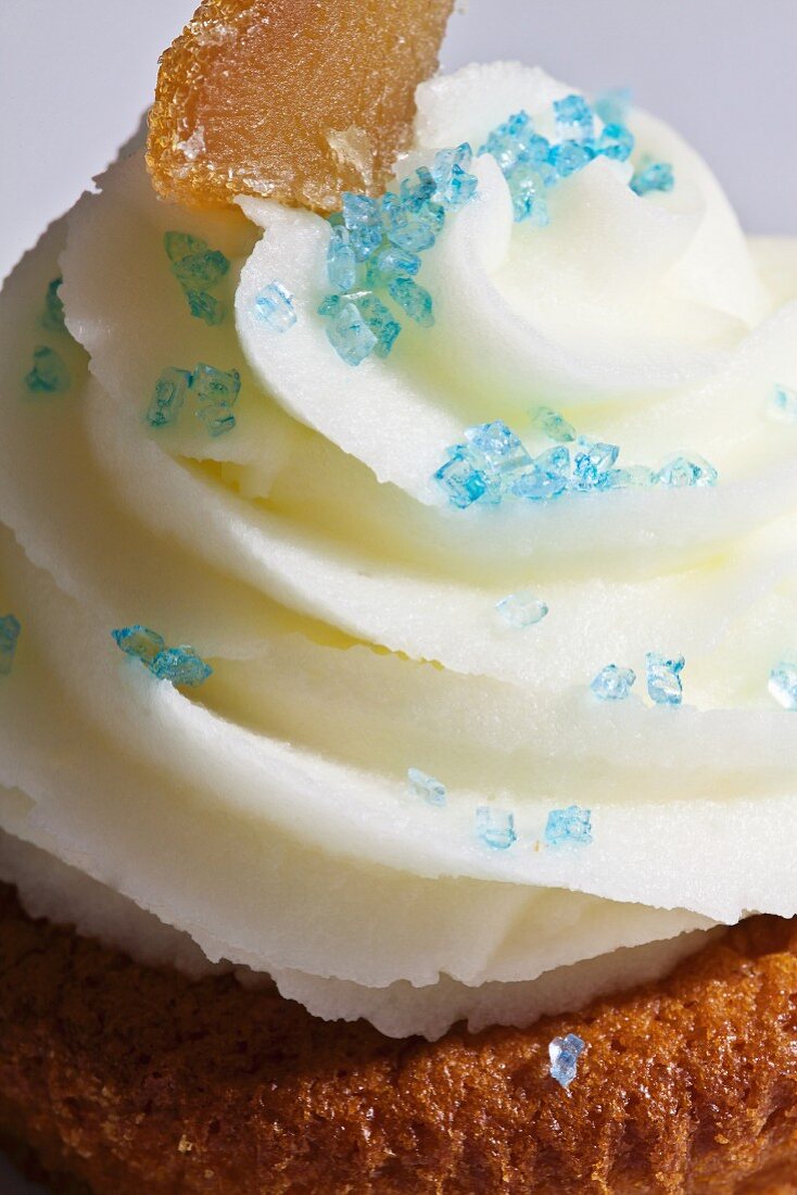 A cupcake topped with white icing and blue sugar (close-up)