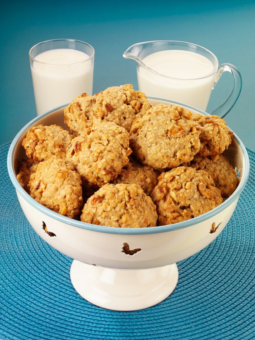 Oat biscuits in a bowl, with a jug of milk and a glass of milk