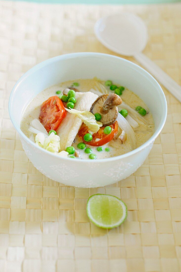 Coconut soup with fish, peas and tomatoes