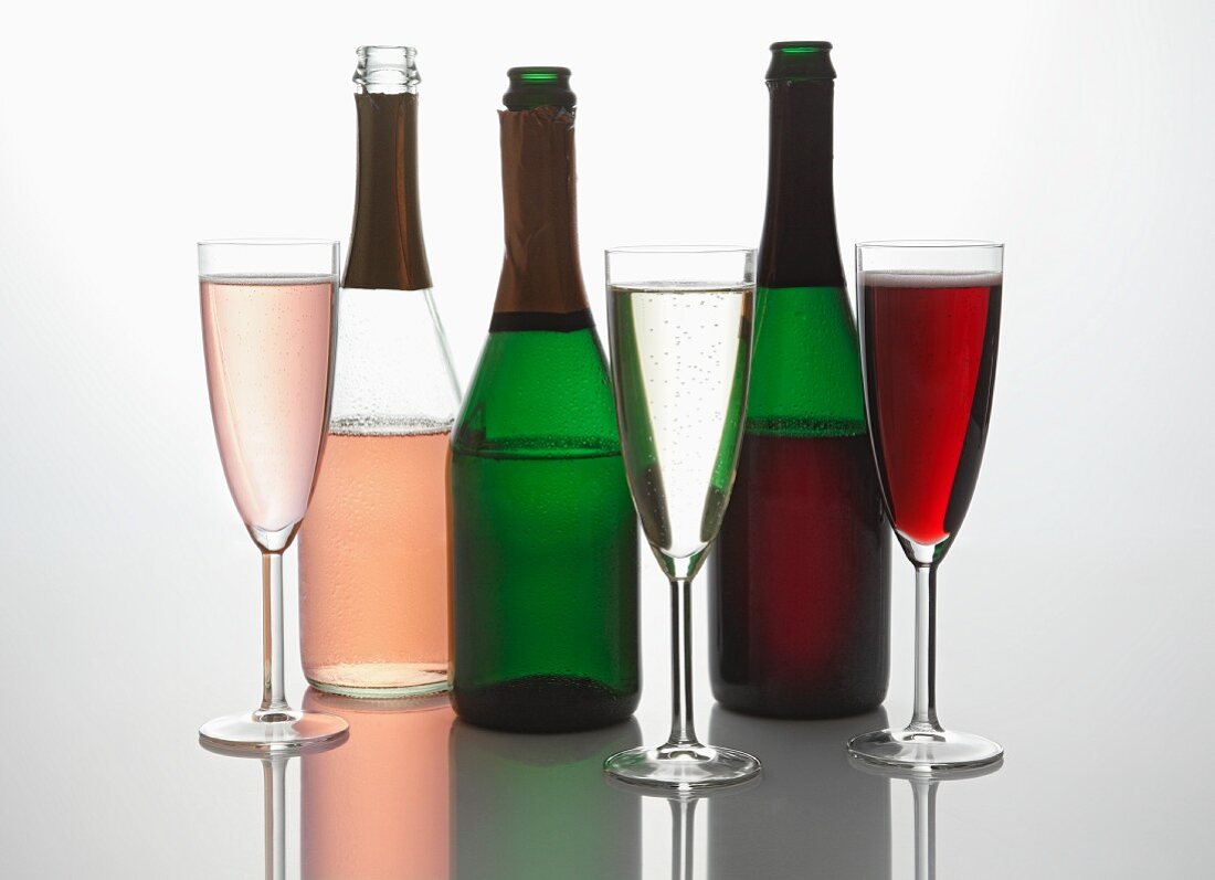 A variety of sparkling wine bottles and glasses of sparkling wine