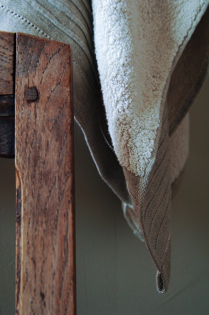 Towel in elegant natural fabrics next to wooden chair back