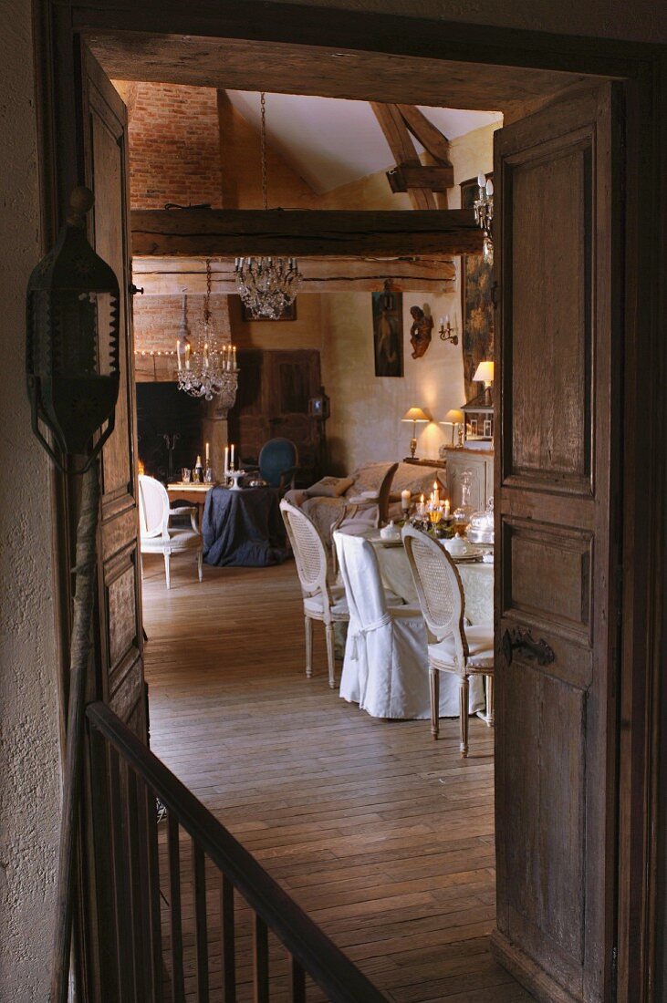 Blick durch offene Flügeltür auf Essplatz und Sitzecke vor Kamin in traditionellem Wohnraum