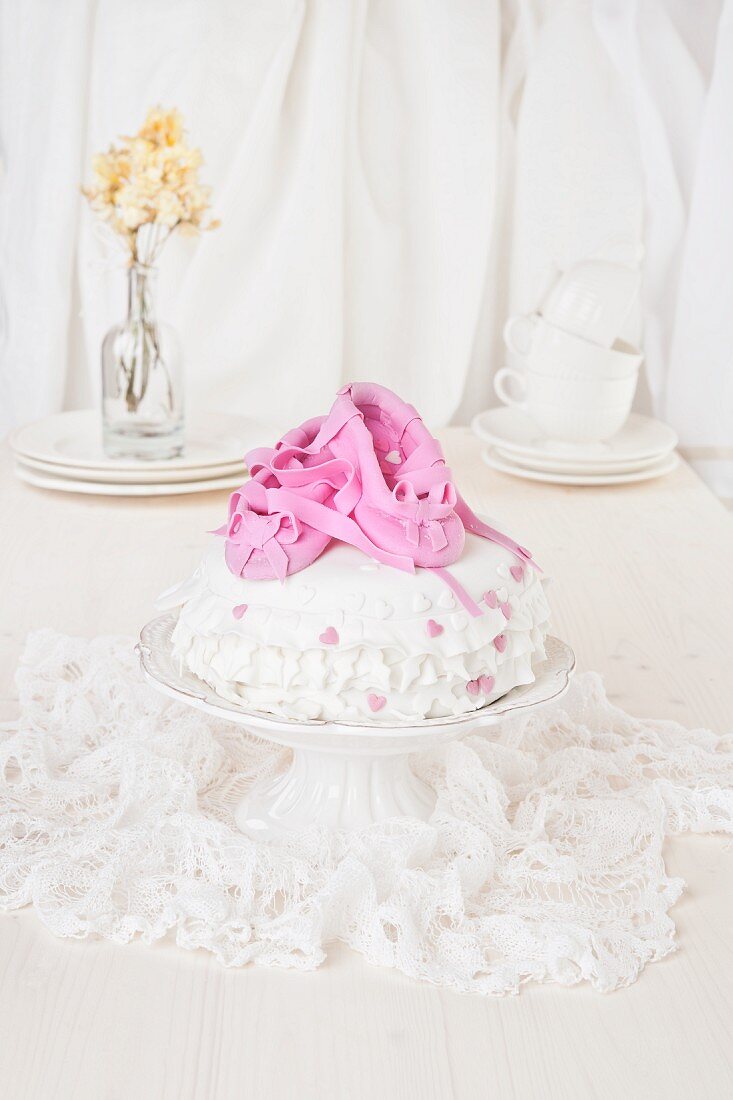 A white-iced birthday cake for a child with pink marzipan ballet slippers