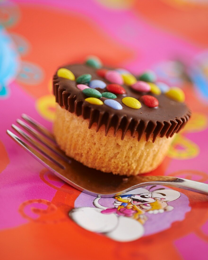 Cupcake mit Schokoglasur und bunten Schokolinsen