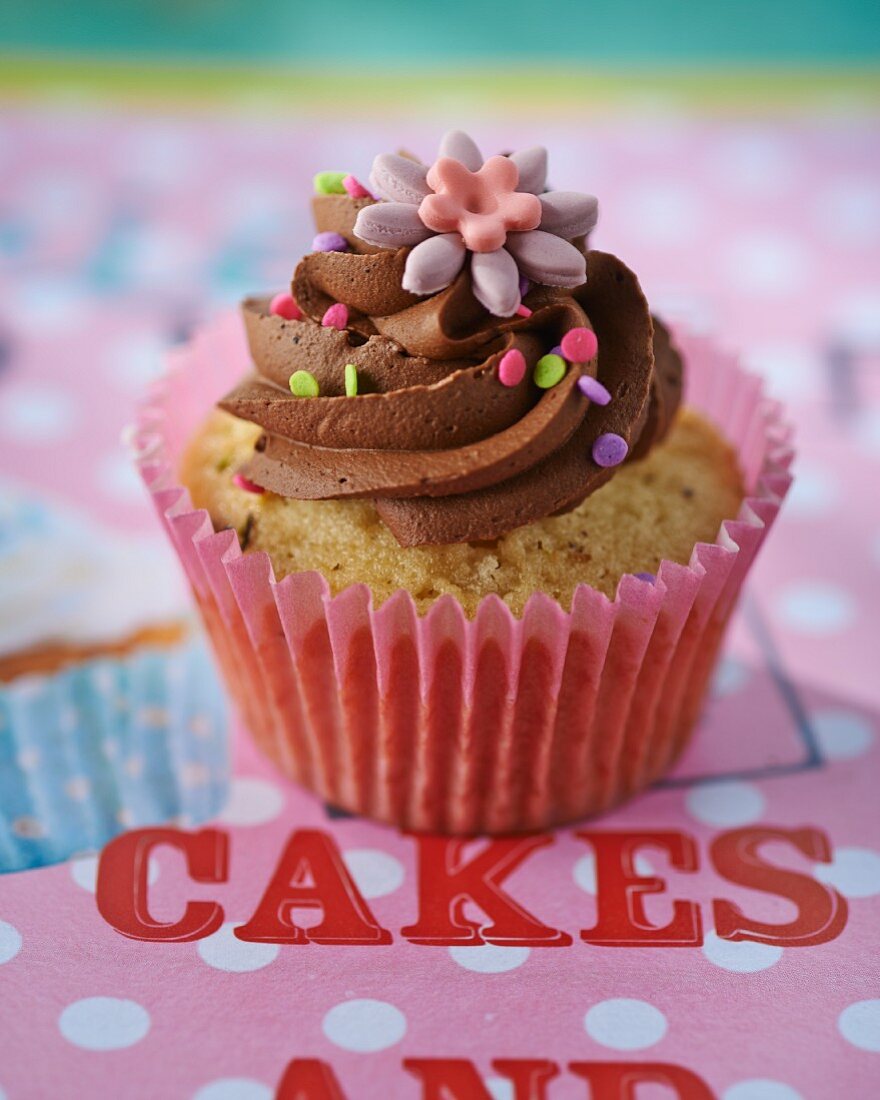 A cupcake topped with chocolate cream and a decorative flower