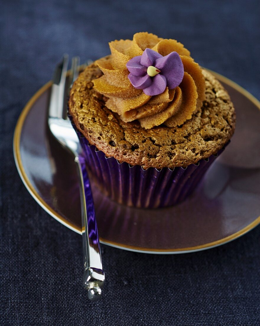 A cupcake with a decorative purple flower
