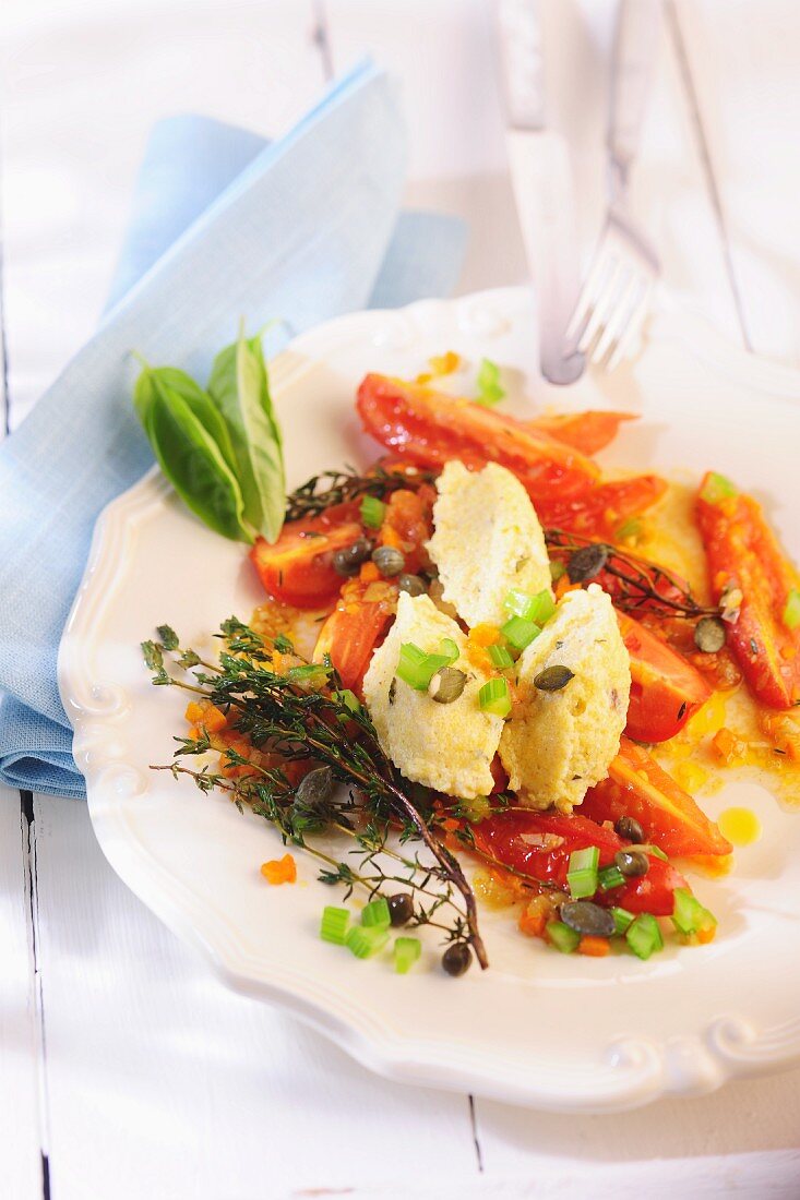 Quenelles of cheese on a plate of tomatoes