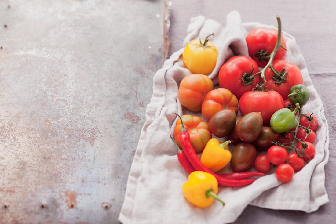 An assortment of tomatoes and chillies on a cloth
