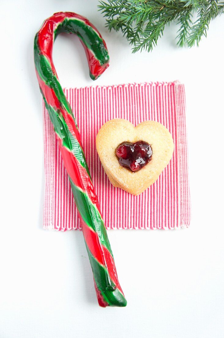 A candy cane and a heart-shaped biscuit with cranberry jam